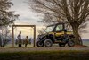 Front three-quarter view of a side x side parked next to people on a swing.