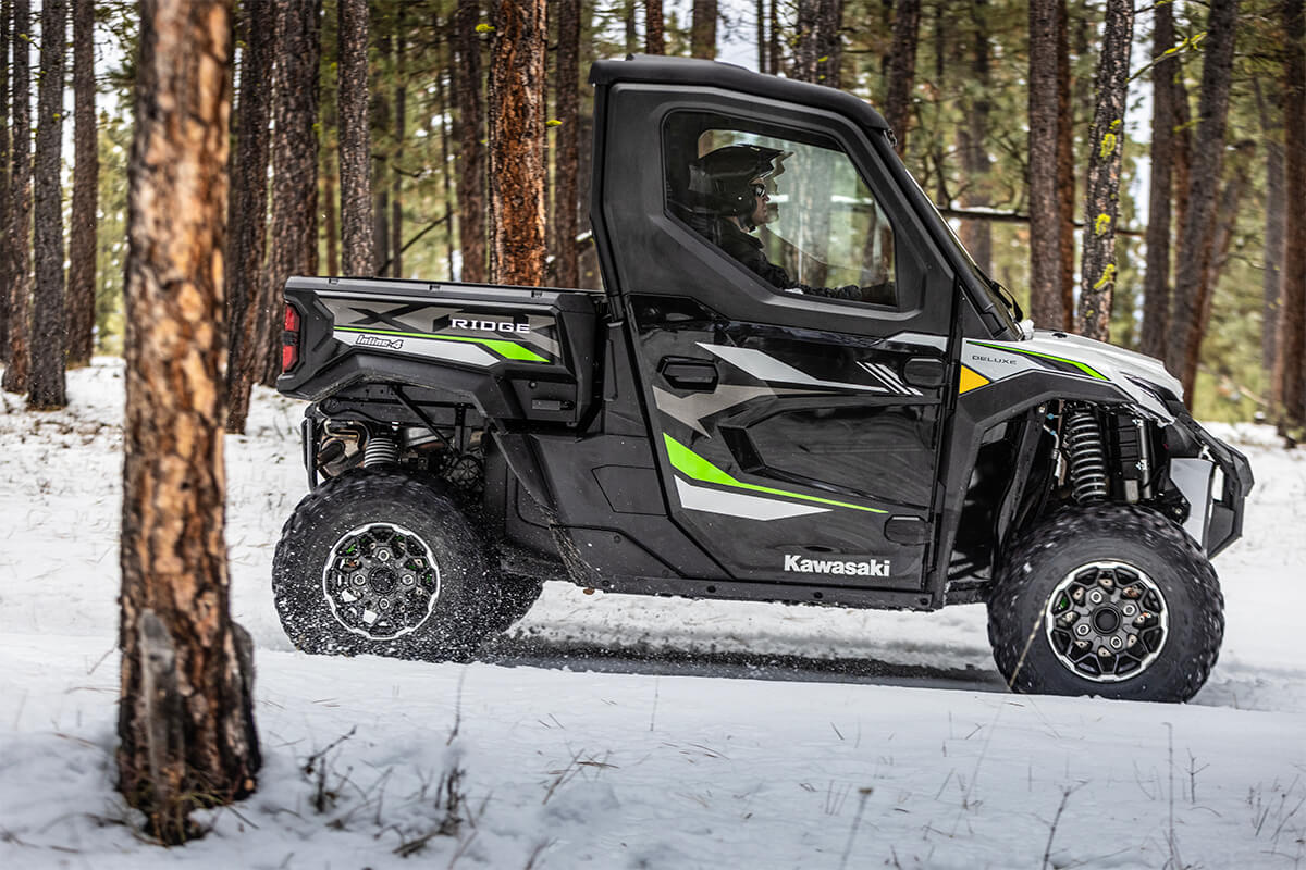 Side view of a person driving a side x side through the snow.