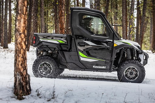 Side view of a person driving a side x side through the snow. opens in a new window