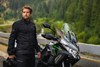 Profile angle of a person standing near a parked motorcycle.