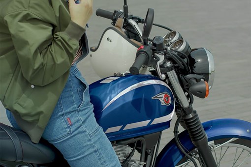 Profile angle of a person seated on a parked motorcycle. opens in a new window