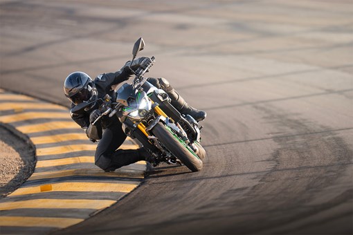 Front angle of a person dragging knee on a motorcycle on the track. opens in a new window