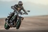 Three-quarter front angle of a person sliding the back tire of a motorcycle on the track.