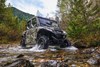 Front three-quarter action photo of a side x side traversing a river.