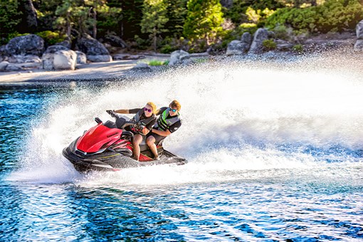 Front angle of two people riding a personal watercraft on the water. opens in a new window