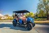Side angle of a family riding in a Neighborhood Activity Vehicle on a community roadway.