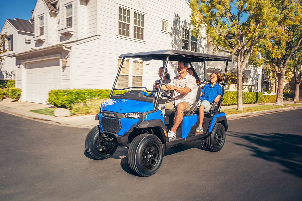 Three-quarter front angle of a family riding in a Neighborhood Activity Vehicle on a community roadway.
