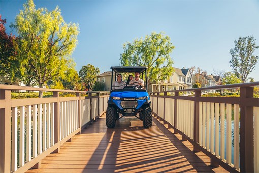 Front angle of a family riding in a Neighborhood Activity Vehicle over a bridge. opens in a new window