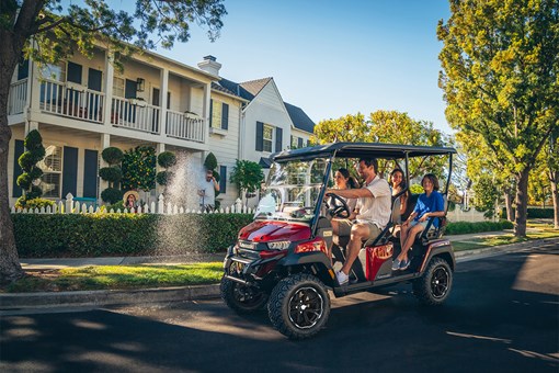 Three-quarter front angle of a family riding in a Neighborhood Activity Vehicle on a community roadway. opens in a new window