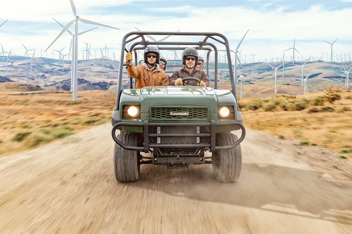 Front angle of four people riding a side x side on a jobsite.