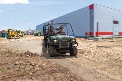 Front angle of three people riding a side x side on a jobsite. opens in a new window