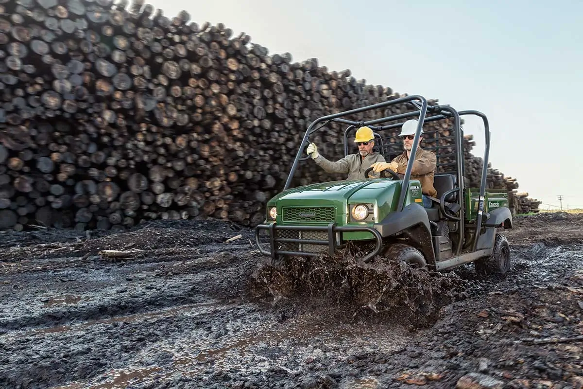 Three-quarter front angle of two people riding a side x side on a jobsite.