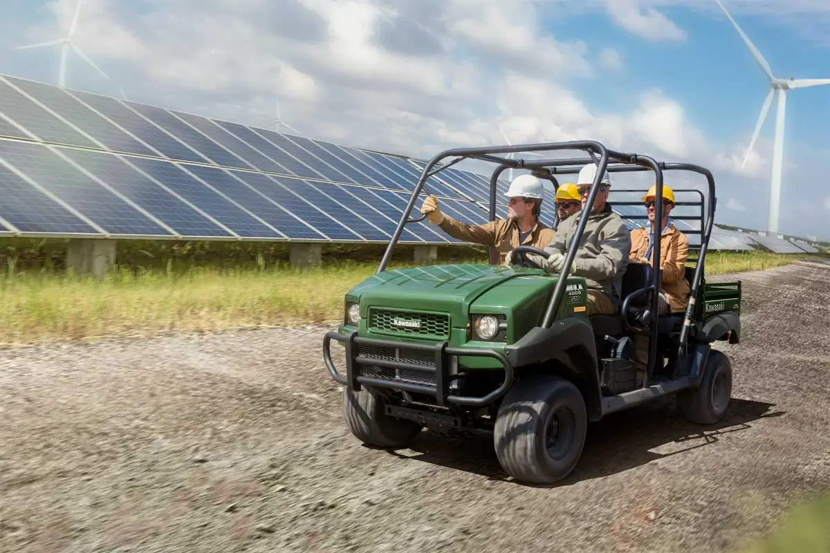 Three-quarter front angle of four people riding a side x side on a jobsite.