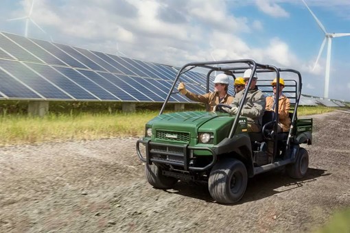 Three-quarter front angle of four people riding a side x side on a jobsite. opens in a new window
