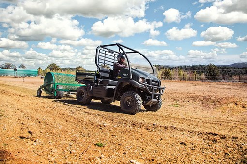 Three-quarter front angle of a person driving a side x side on a ranch. opens in a new window
