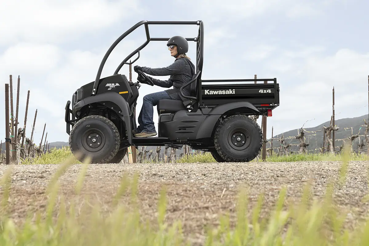 Side angle of a person driving a side x side on a ranch.