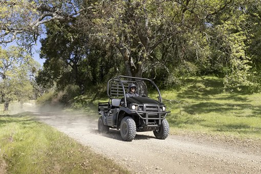 Three-quarter front angle of a person driving a black side x side on a ranch. opens in a new window