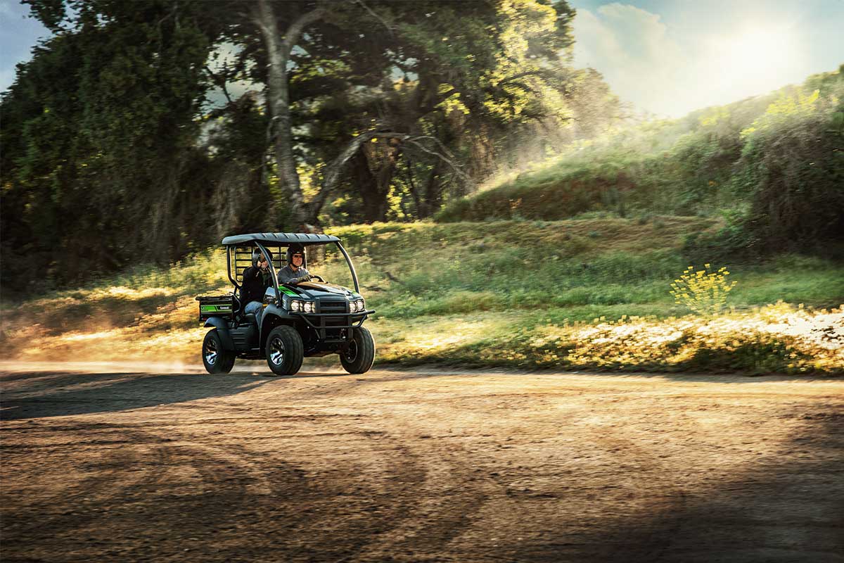 Three-quarter front angle of two people driving a side x side off-road.