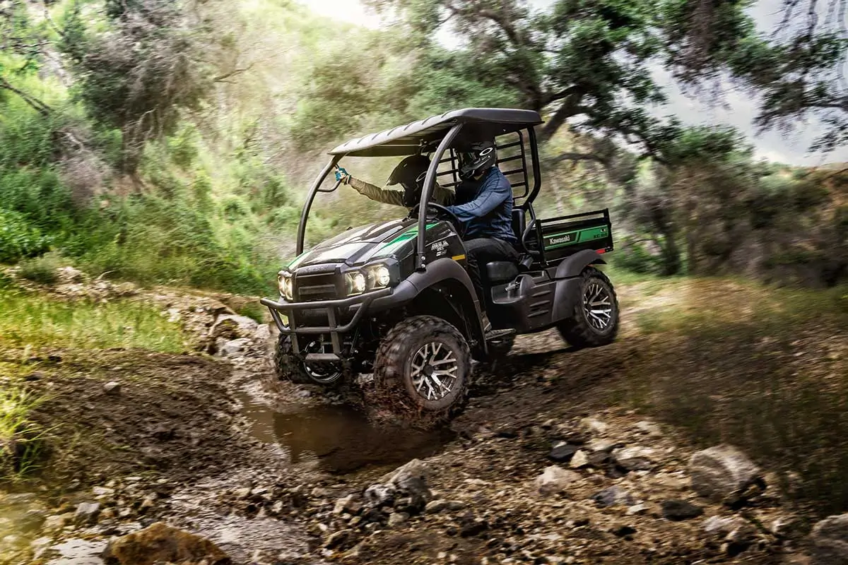 Side angle of two people driving a side x side off-road.