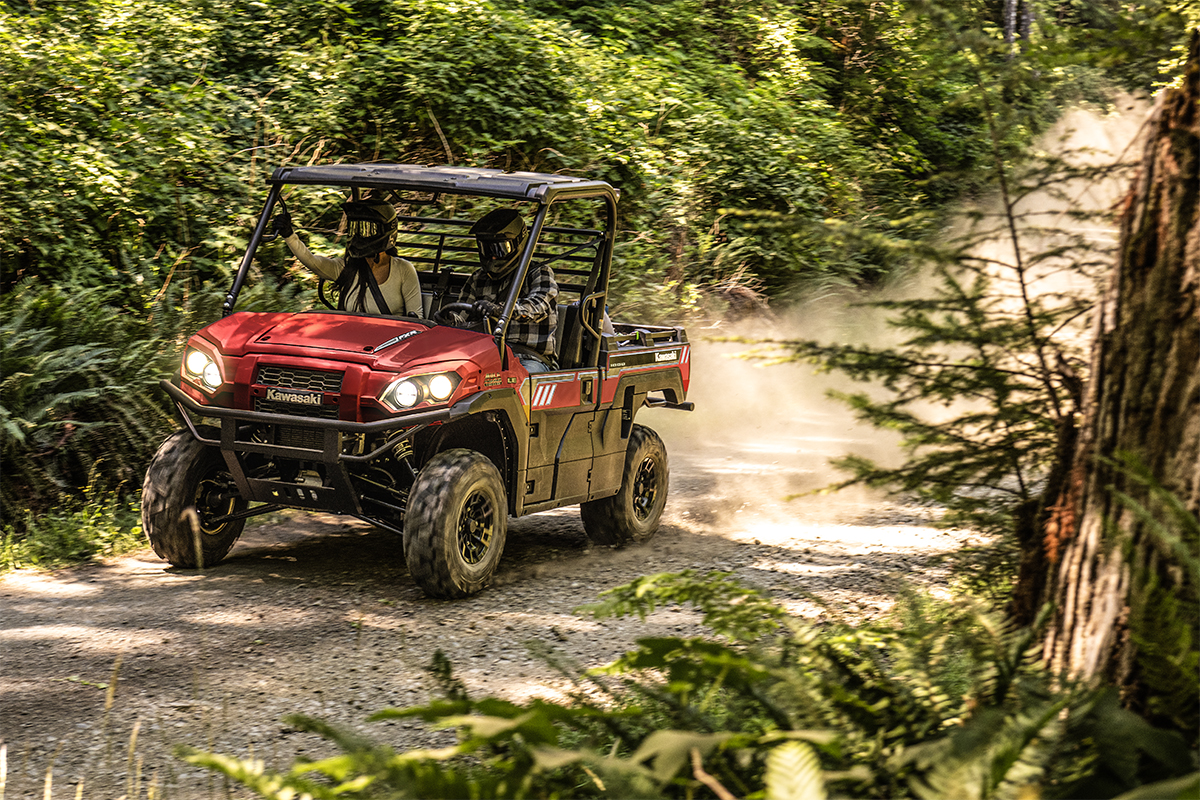 Three-quarter front angle of two people driving a side x side off-road.
