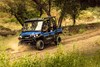 Three-quarter front angle of four people driving a side x side off-road.