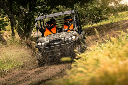 Front angle of four people driving a side x side off-road. opens in a new window