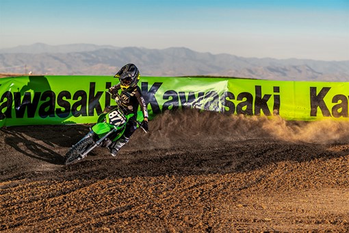 Front angle of a person riding a motorcycle around a bend on a dirt track. opens in a new window