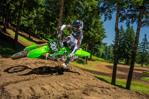 Front angle of a person riding a motorcycle over a small jump on a dirt track. opens in a new window