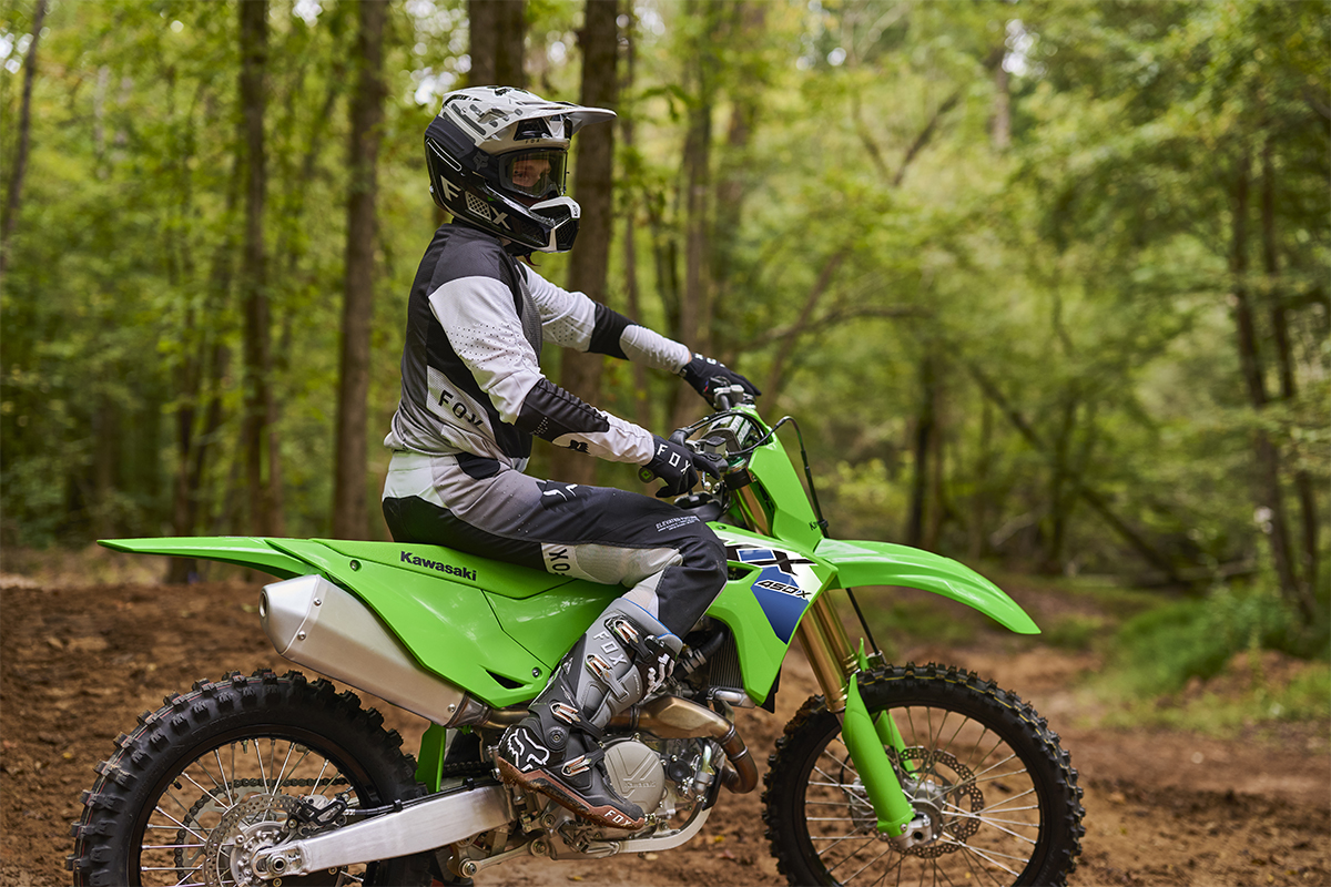 Side angle of a person seated on a motorcycle parked on an off-road course.