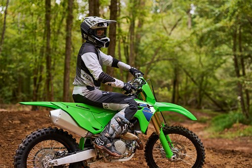 Side angle of a person seated on a motorcycle parked on an off-road course. opens in a new window
