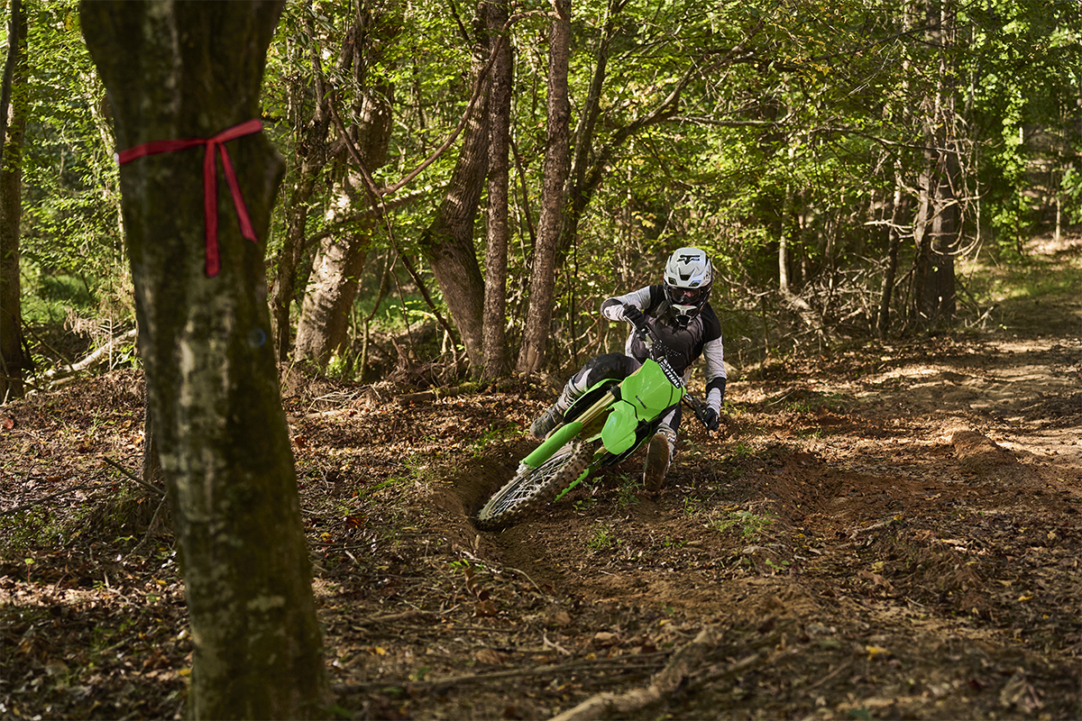 Front angle of a person riding a motorcycle around a bend on an off-road course.
