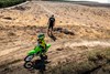 Aerial angle of a person riding a motorcycle off-road under adult supervision.