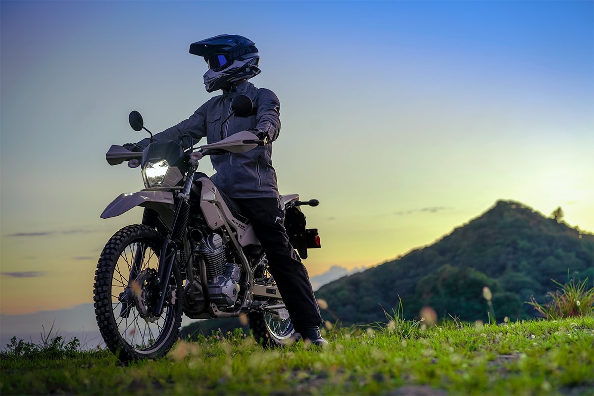 Three-quarter front angle of a person seated on a motorcycle off-road.