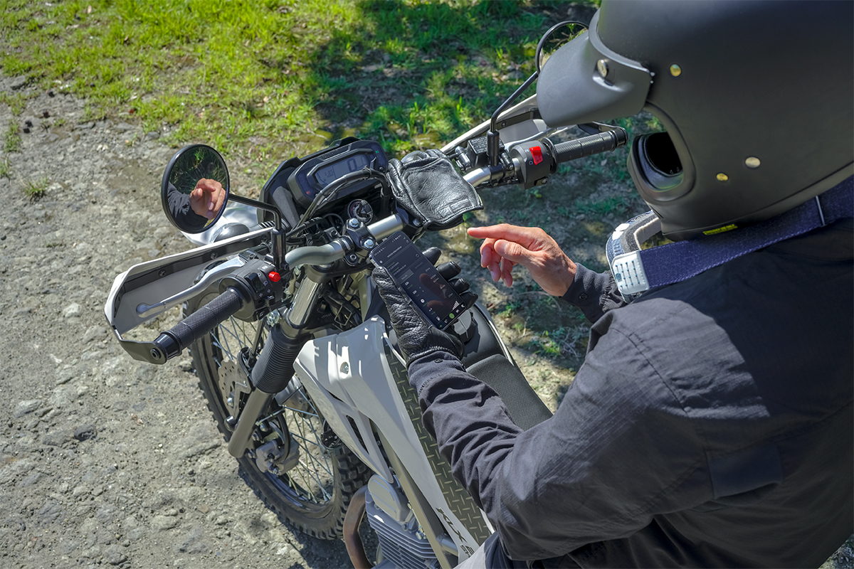 Rider POV of the handlebars and smartphone connectivity of a stationary motorcycle.