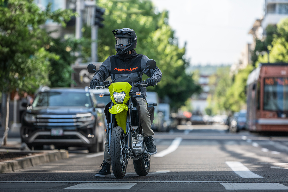 Front angle of a person riding a motorcycle paused at a traffic light.