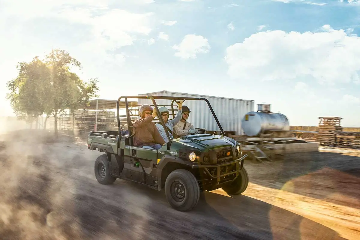 Three-quarter front angle of three people riding in a side x side at a jobsite.