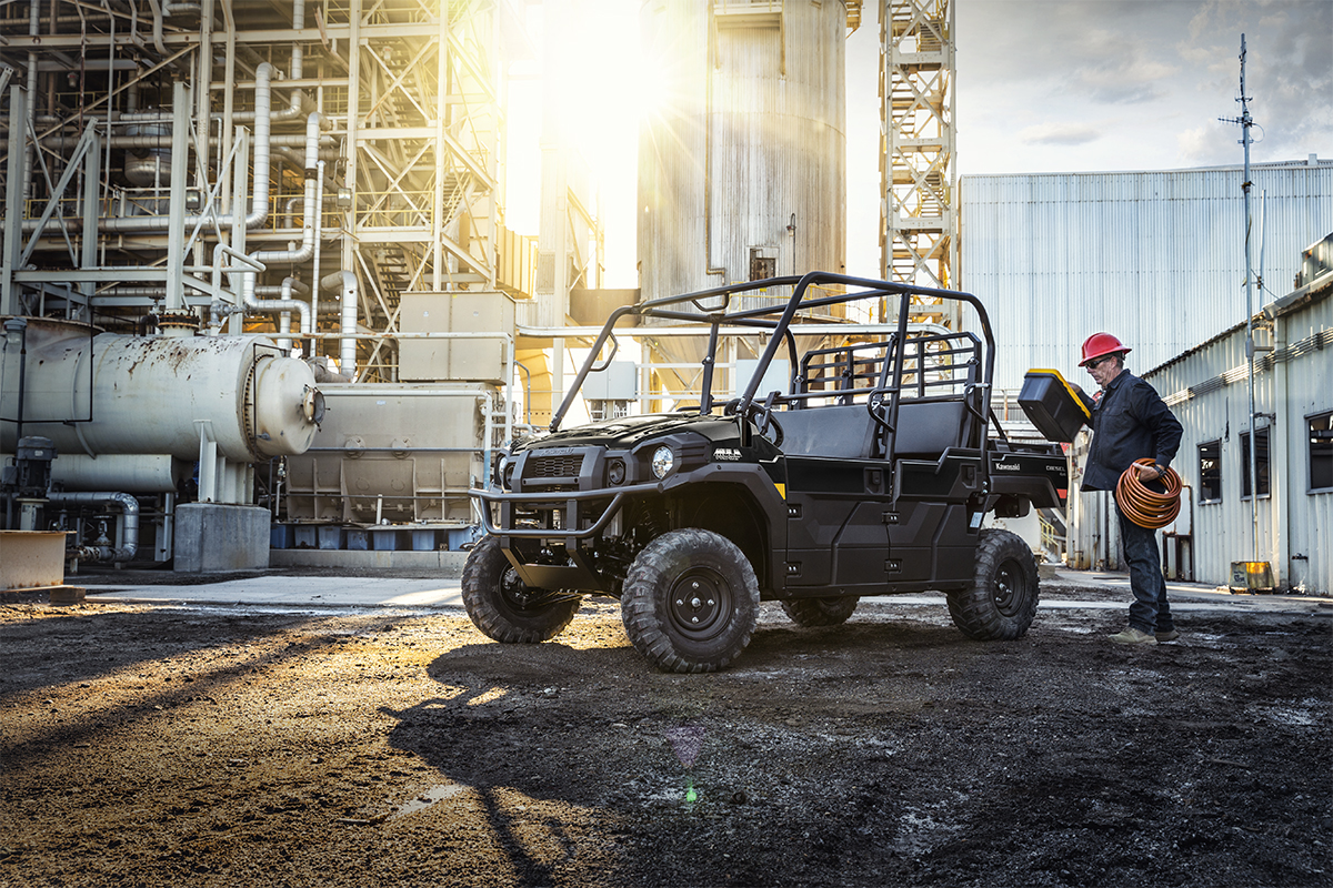 Three-quarter front angle of a person loading the bed of a parked side x side at a jobsite.