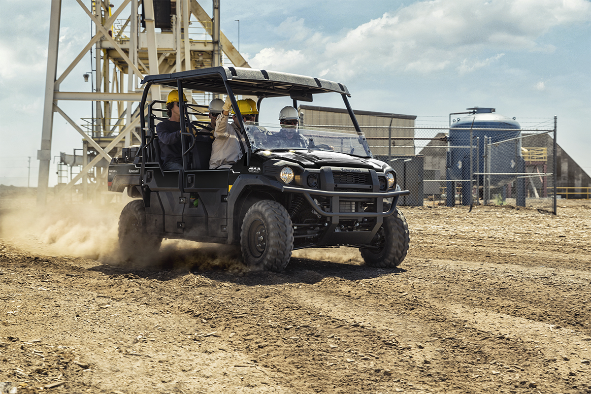 Three-quarter front angle of five people riding in a side x side at a jobsite.