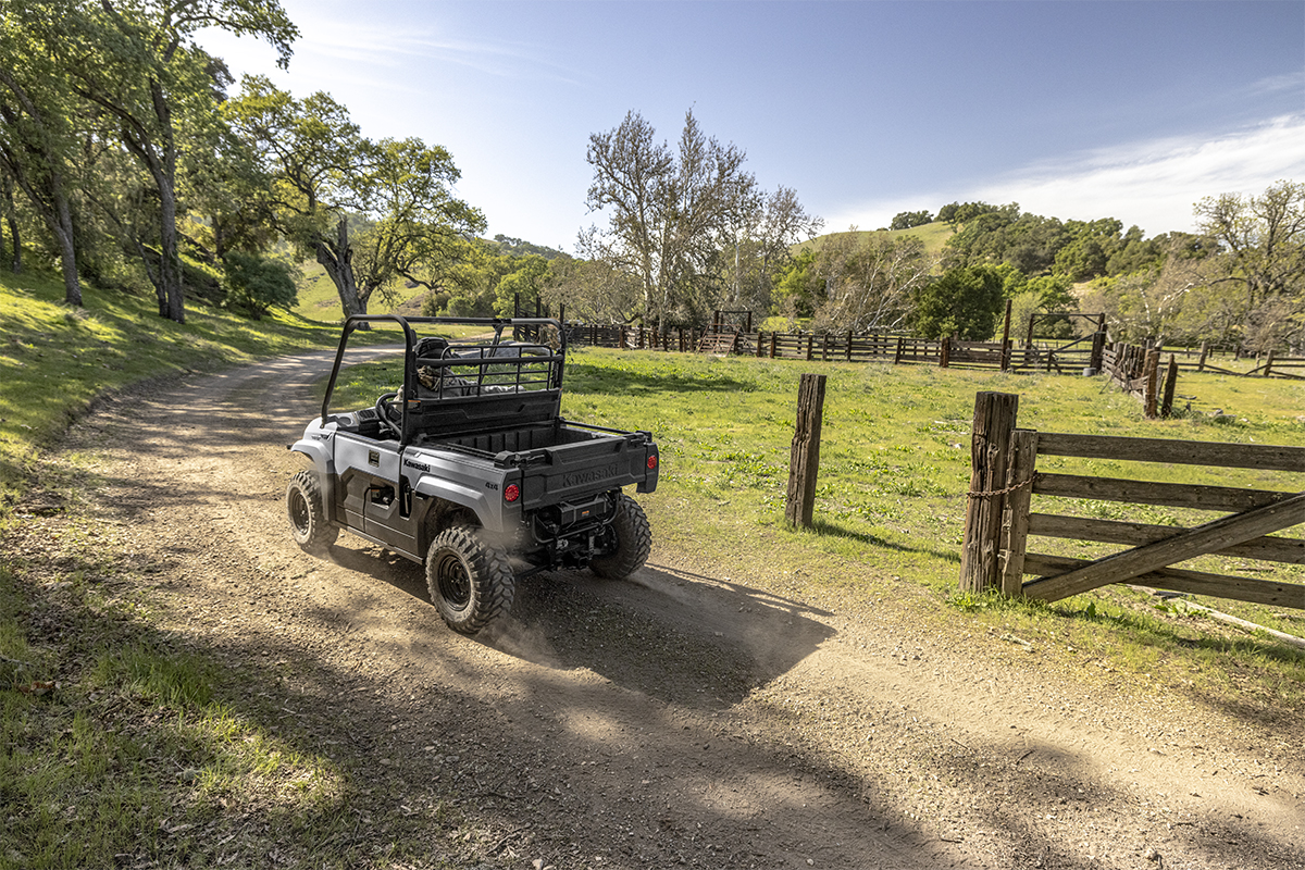 Three-quarter rear angle of a person driving a side x side on a ranch.