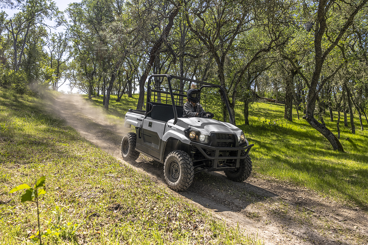 Three-quarter front angle of a person driving a side x side downhill on a ranch.