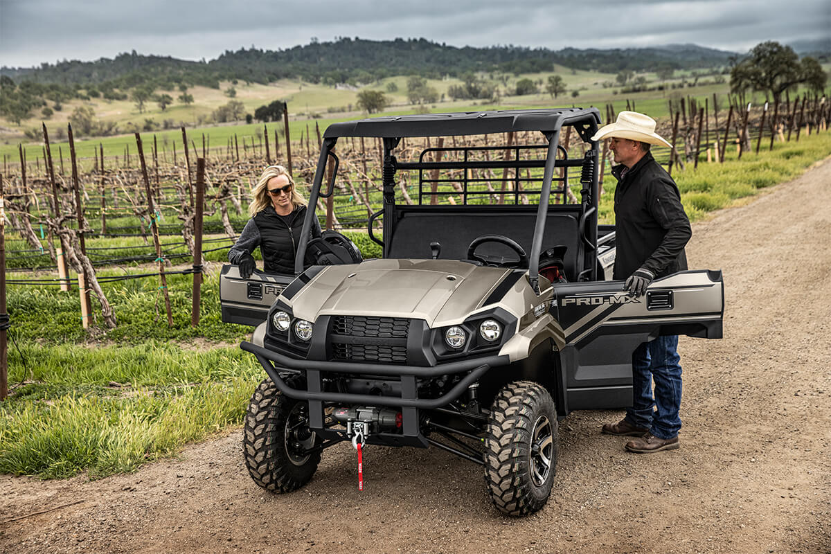 Three-quarter front angle of a two people entering a side x side off-road.