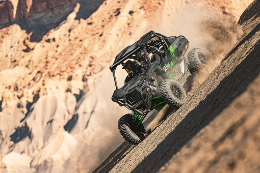 Three-quarter front angle of two people driving a black side x side off-road. opens in a new window