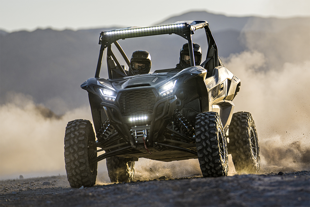 Front angle of two people driving a side x side off-road.