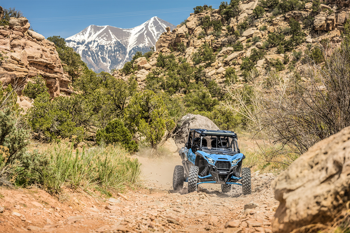 Front angle of four people driving a side x side off-road.