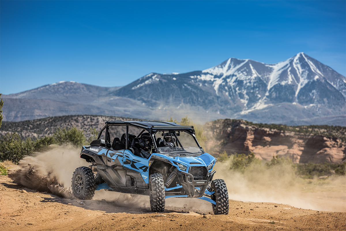 Three-quarter front angle of three people driving a side x side off-road.
