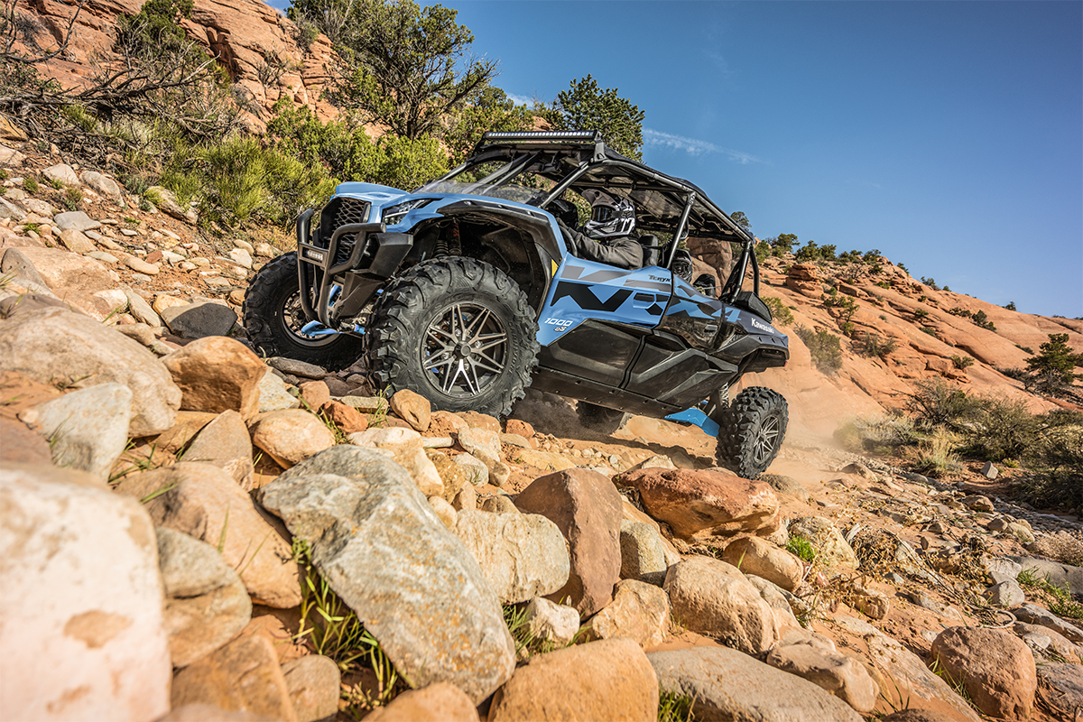 Side angle of three people driving a side x side off-road.