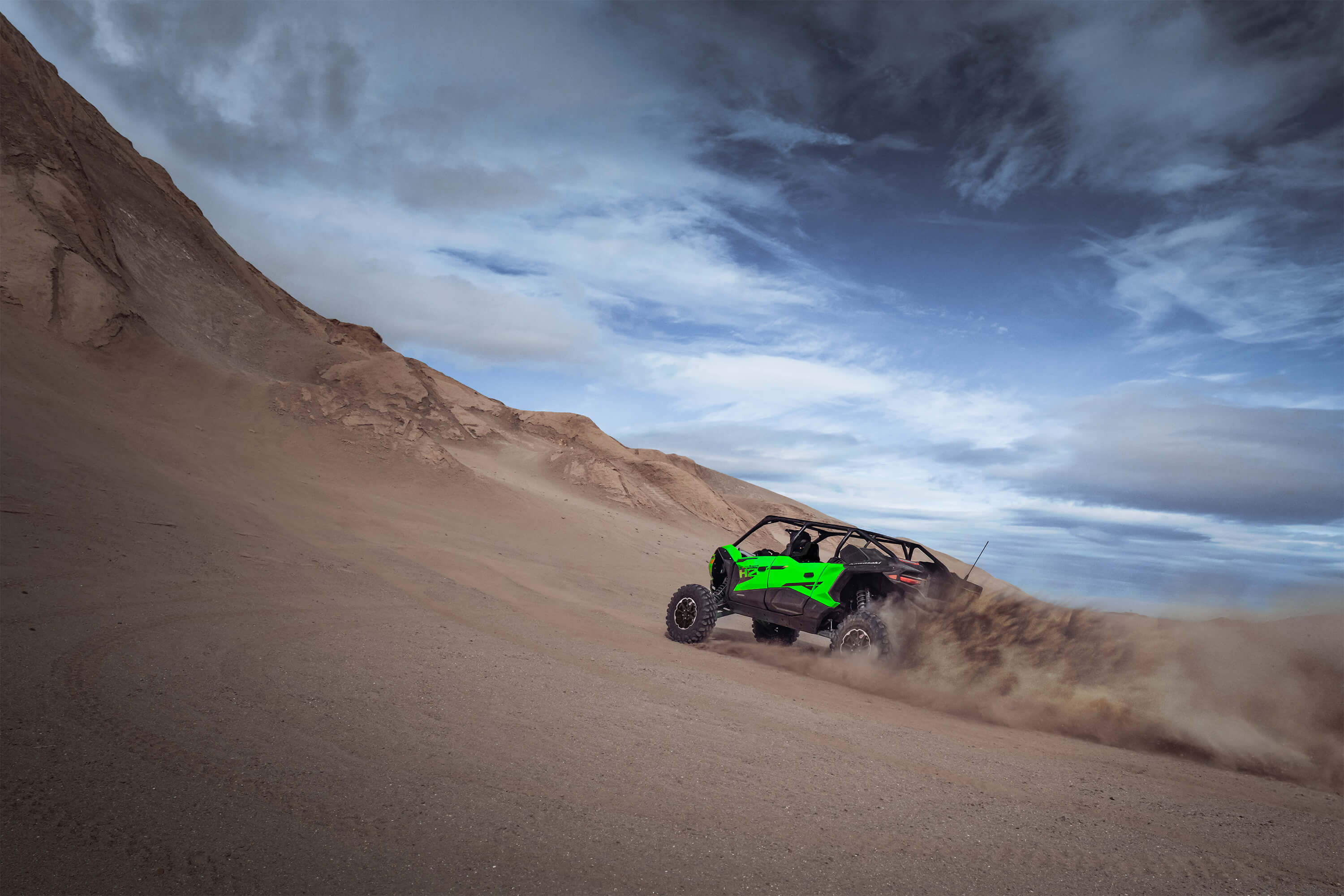 Rear angle of a person driving a side x side going up hill off-road.