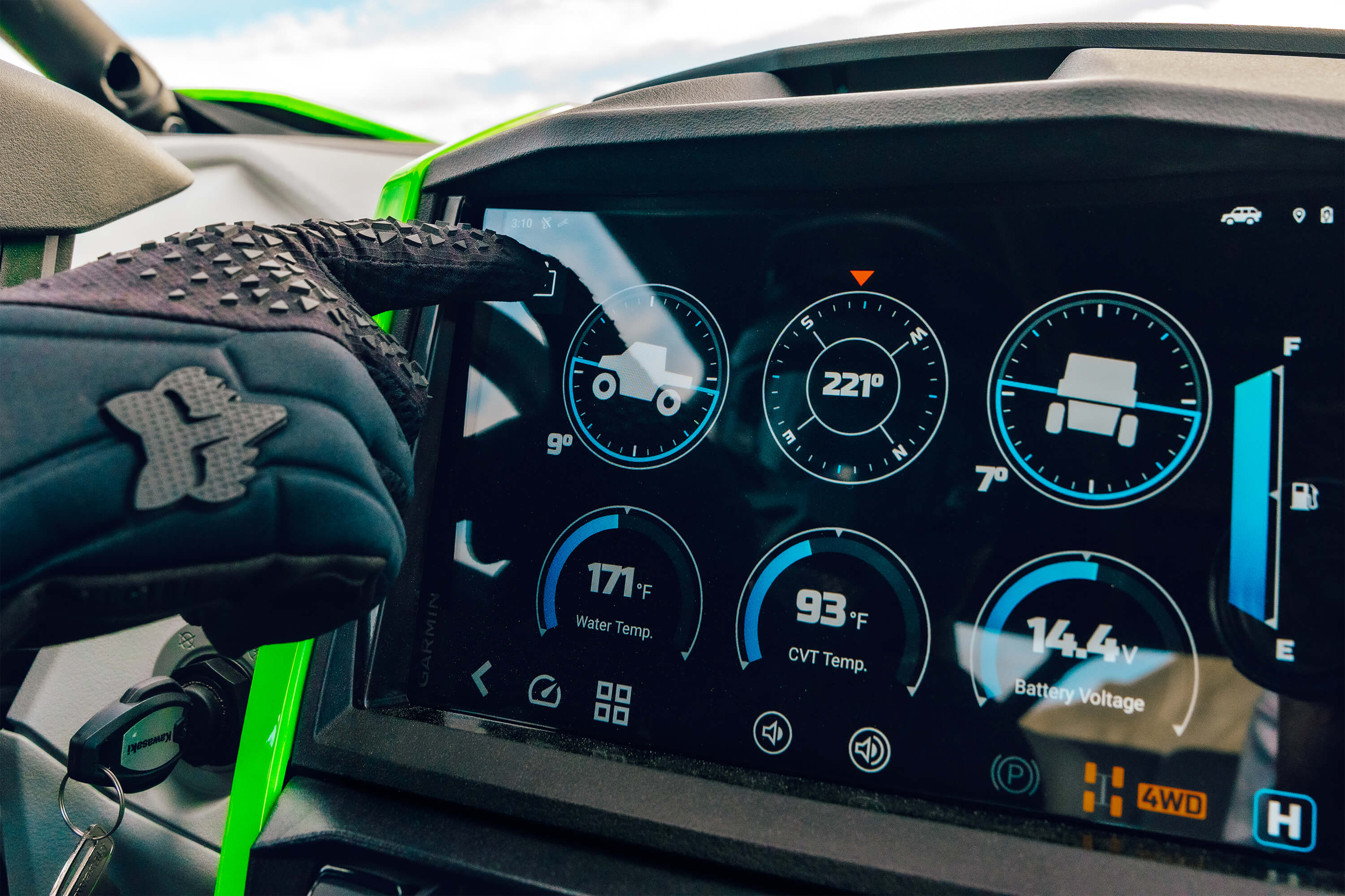 POV of infotainment screen of a side x side with drivers hand in view.