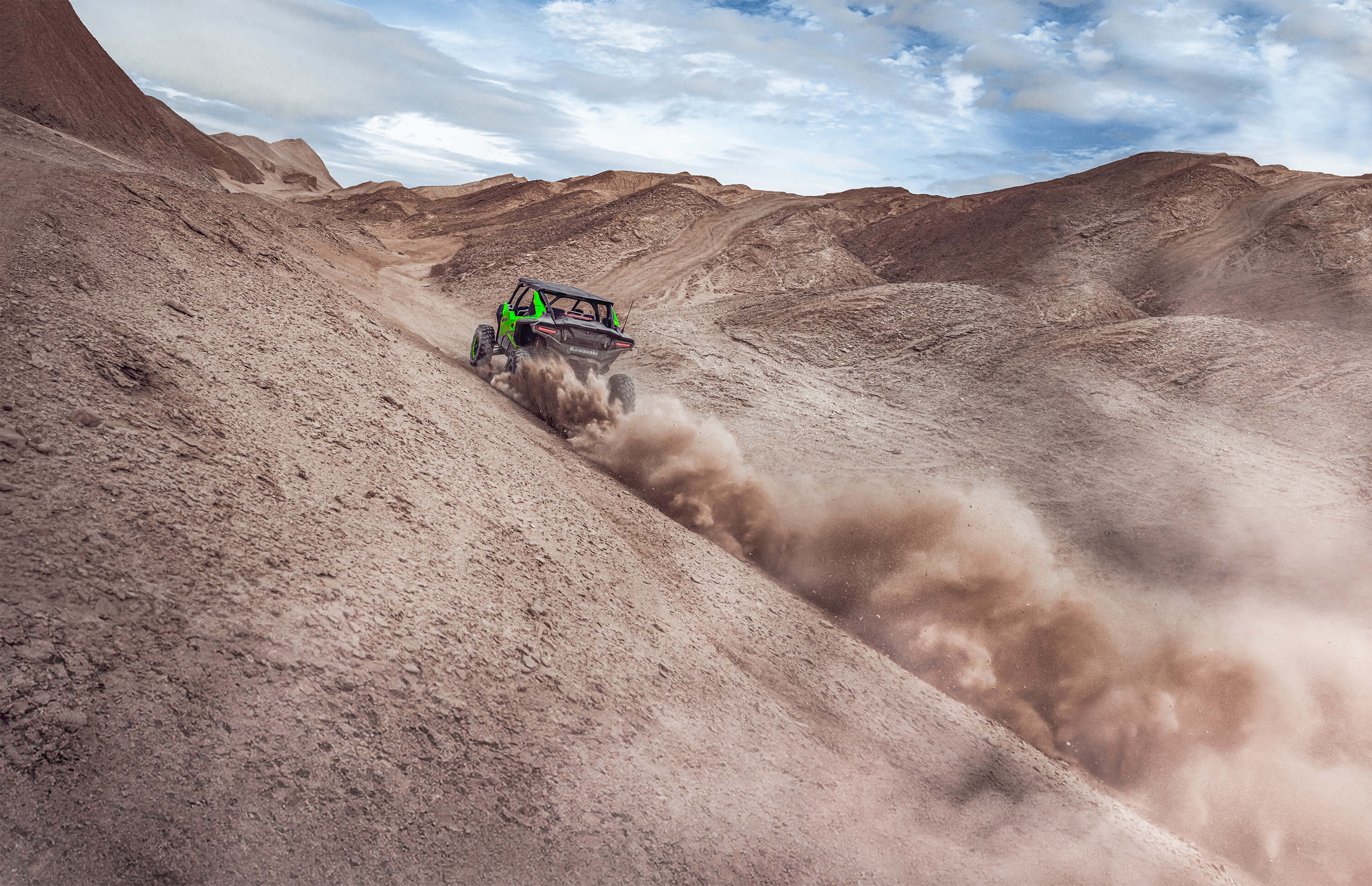 Front angle of a person driving a side x side off-road up the side of a sand dune.