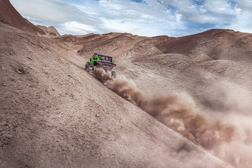 Front angle of a person driving a side x side off-road up the side of a sand dune. opens in a new window
